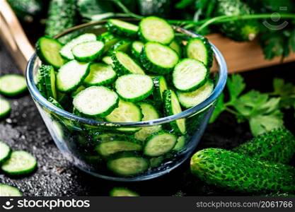 Ripe sliced cucumber in a bowl. On a black background. High quality photo. Ripe sliced cucumber in a bowl.
