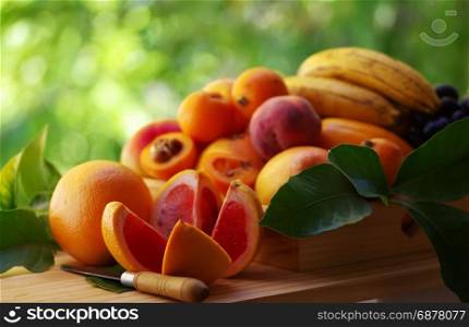 ripe sliced toranja and various fruits on wooden basket