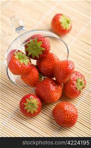 ripe strawberries falling from glass bowl