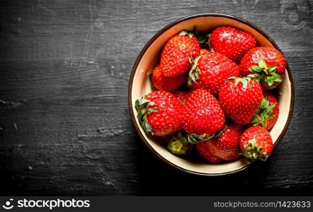Ripe strawberries in a bowl. On the black wooden table.. Ripe strawberries in a bowl.