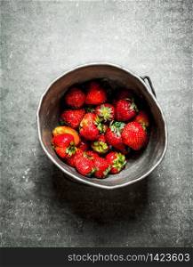Ripe strawberries in an old pot. On the stone table.. Ripe strawberries in an old pot.
