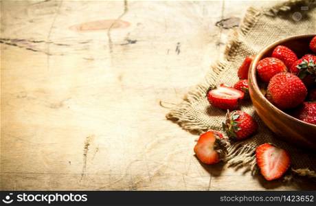Ripe strawberries in bowl on a sack. On wooden background.. Ripe strawberries in bowl on a sack.