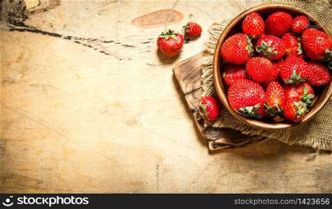 Ripe strawberries in bowl on Board. On wooden background.. Ripe strawberries in bowl on Board.