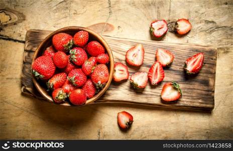 Ripe strawberries in bowl on Board. On wooden background.. Ripe strawberries in bowl on Board.