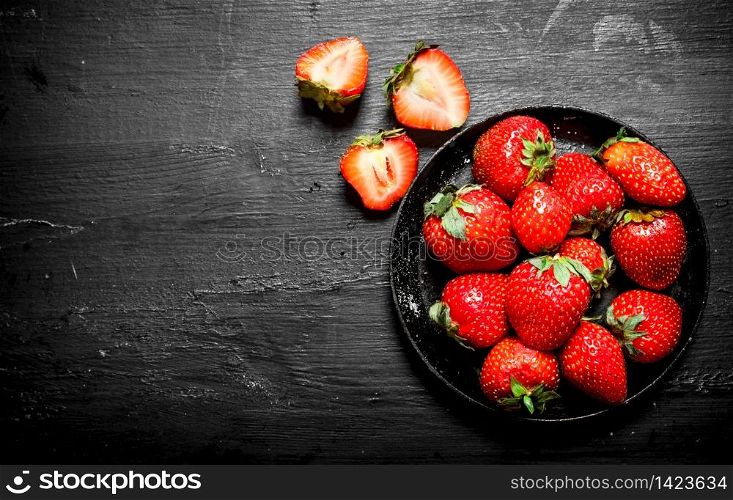 Ripe strawberries old plate. On the black wooden table.. Ripe strawberries old plate.