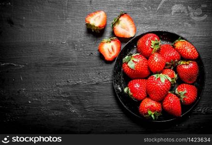 Ripe strawberries old plate. On the black wooden table.. Ripe strawberries old plate.