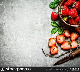 Ripe strawberries with an old knife. On the stone table.. Ripe strawberries with an old knife.
