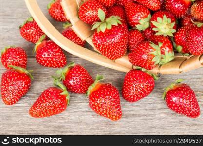 Ripe strawberry in wicker basket on a wooden background