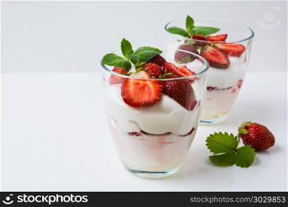 Ripe strawberry summer cream dessert . Summer layered dessert with ripe strawberry and whipped cream on the white background, copy space