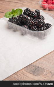 Ripe sweet blackberries and raspberries on wood table background