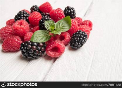 Ripe sweet raspberries and blackberries on wood table background