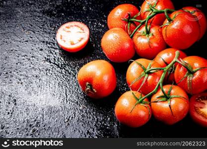 Ripe tomatoes on a branch and tomato halves. On a black background. High quality photo. Ripe tomatoes on a branch and tomato halves.