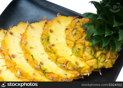 ripe vibrant pineapple sliced on a black plate