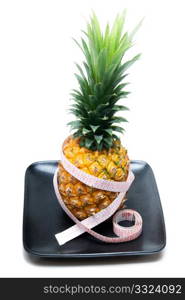 ripe vivid pineapple on a black plate with tape meter