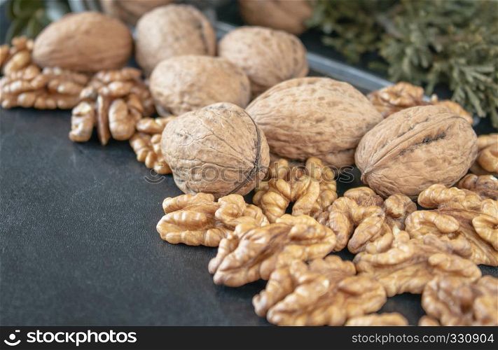 Ripe whole walnuts and peeled walnut kernels against a black background.. Walnut kernels near whole nuts on a black background.