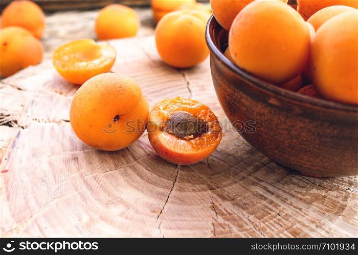 Ripe yellow apricots in a bowl on a wooden table near the apricot. Close-up.. Ripe yellow apricots in a bowl on a wooden table near the apricot.