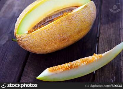 Ripe yellow melon with seeds on a brown wooden background