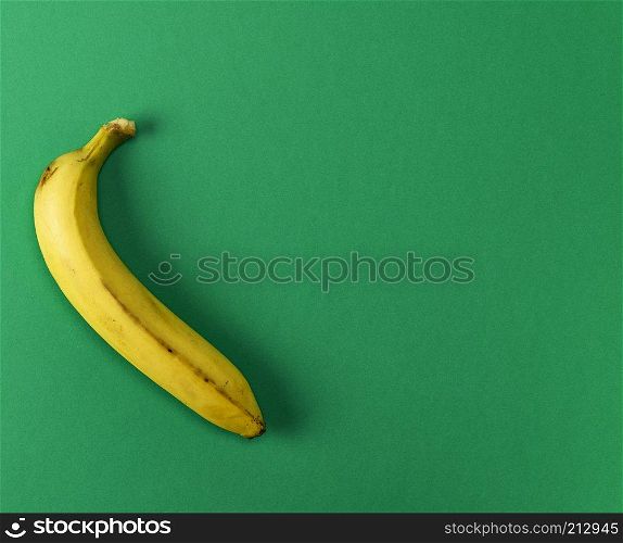 ripe yellow one banana on a green background, copy space