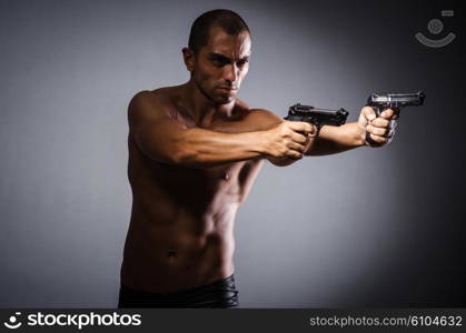 Ripped man with gun against grey background