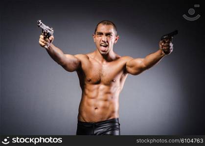 Ripped man with gun against grey background