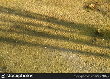 Rippled water background pattern. Rippled water background pattern in warm sun light with shadow of tree