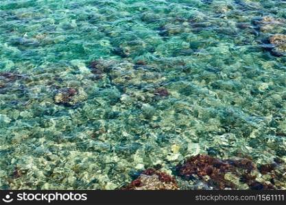 Rippled water surface from above and stony sea bottom - Abstract background