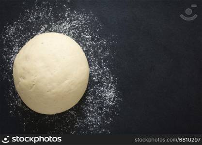 Risen or proved yeast dough for bread or pizza on a floured slate surface, photographed overhead with natural light (Selective Focus, Focus on the top of the dough)