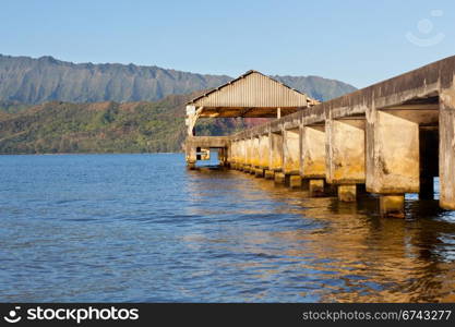 Rising sun illuminates the Hanalei pier and Na Pali mountains in Kauai