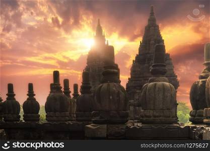 Rising sun shining behind Candi Prambanan or Rara Jonggrang Hindu temple located near Yogyakarta, Java, Indonesia. Beautiful shot with morning sunrise and ancient architectural ensemble