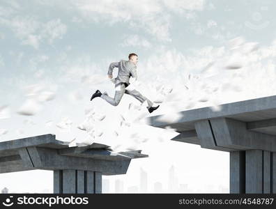 Risk concept. Image of young businessman jumping over gap in bridge