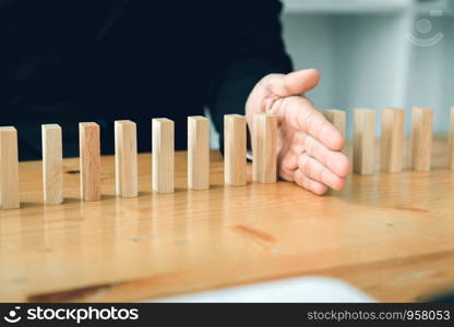 Risk concept with hand of businessman stopping and protection the domino effect.