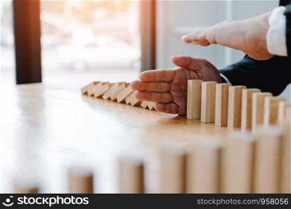 Risk concept with hand of businessman stopping and protection the domino effect.