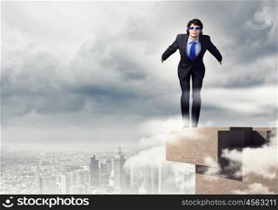 Risk in business. Image of young businessman in goggles jumping from top of building