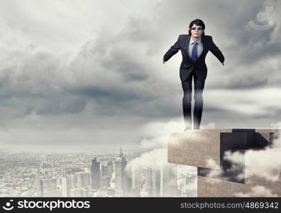 Risk in business. Image of young businessman in goggles jumping from top of building