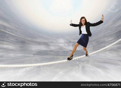 Risk in business. Young attractive businesswoman balancing on rope high in sky