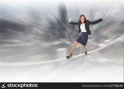 Risk in business. Young attractive businesswoman balancing on rope high in sky