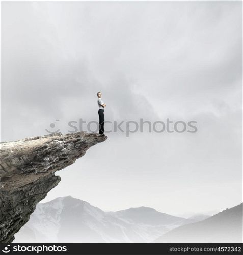 Risky business. Attractive businesswoman standing on edge of mountain