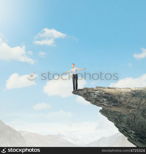 Risky business. Attractive businesswoman standing on edge of mountain