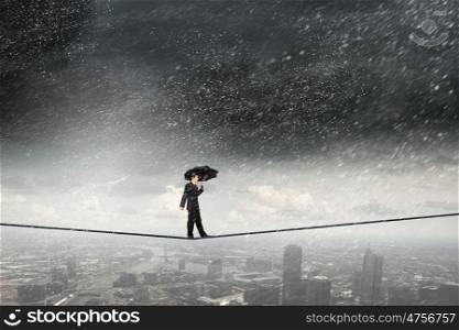 Risky business. Businessman with umbrella balancing on rope high on sky
