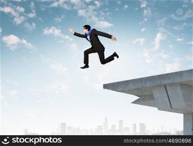 Risky business. Image of jumping businessman at the edge of bridge