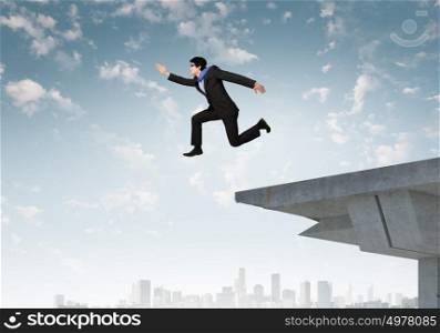 Risky business. Image of jumping businessman at the edge of bridge
