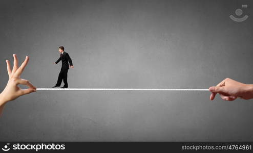 Risky business. Young brave ricky businessman balancing on rope