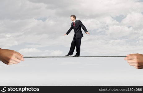 Risky business. Young brave ricky businessman balancing on rope