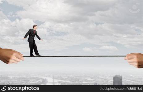 Risky business. Young brave ricky businessman balancing on rope