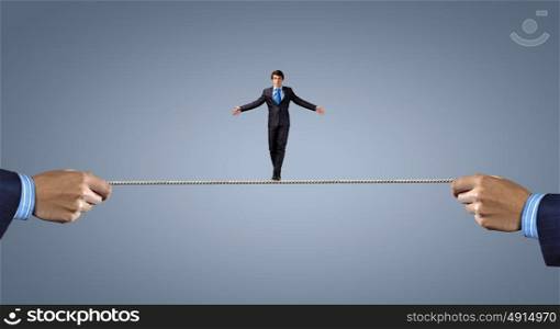 Risky business. Young brave ricky businessman balancing on rope