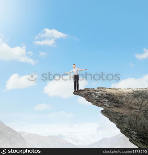 Risky business. Young businesswoman balancing on edge of hill top