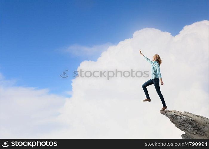 Risky step. Young woman on rock edge making step above gap