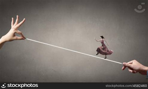 Risky woman. Woman in evening dress and blindfold walking on rope