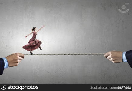 Risky woman. Woman in evening dress and blindfold walking on rope