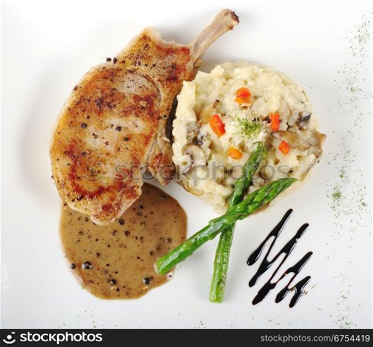 Risotto, green asparagus and meat with gravy on a garnished white plate photographed from above . Risotto, Asparagus and Meat